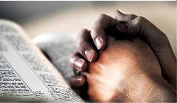 Mani giunte in preghiera su una pagina della Bibbia